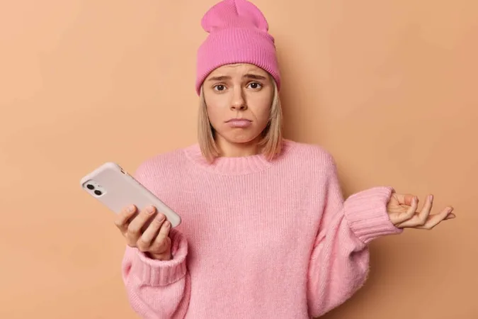 Chica disgustada mirando su teléfono, posiblemente reaccionando a ser bloqueada en las redes sociales. Chica disgustada mirando su teléfono, posiblemente reaccionando a ser bloqueada en las redes sociales.