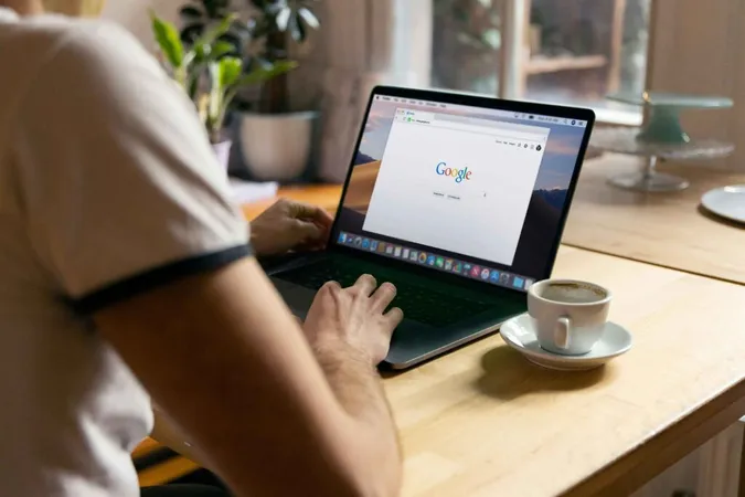 A man pasting something into the Google search bar on a laptop.