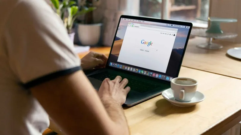 A man pasting something into the Google search bar on a laptop.