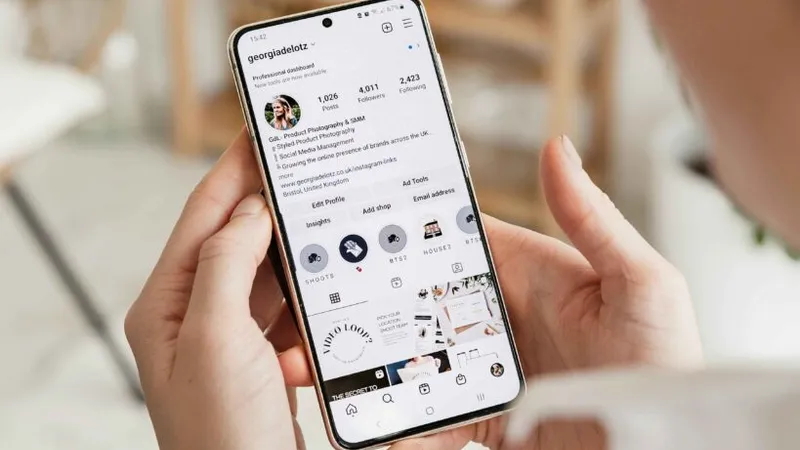A young woman is looking at an Instagram profile on her smartphone,.