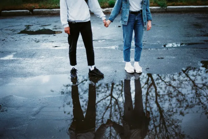 Two people standing on a wet road, holding hands Two people standing on a wet road, holding hands