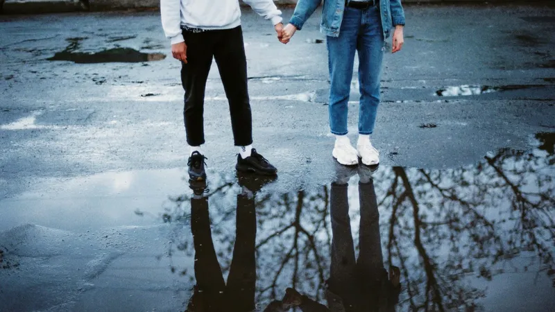 Two people standing on a wet road, holding hands