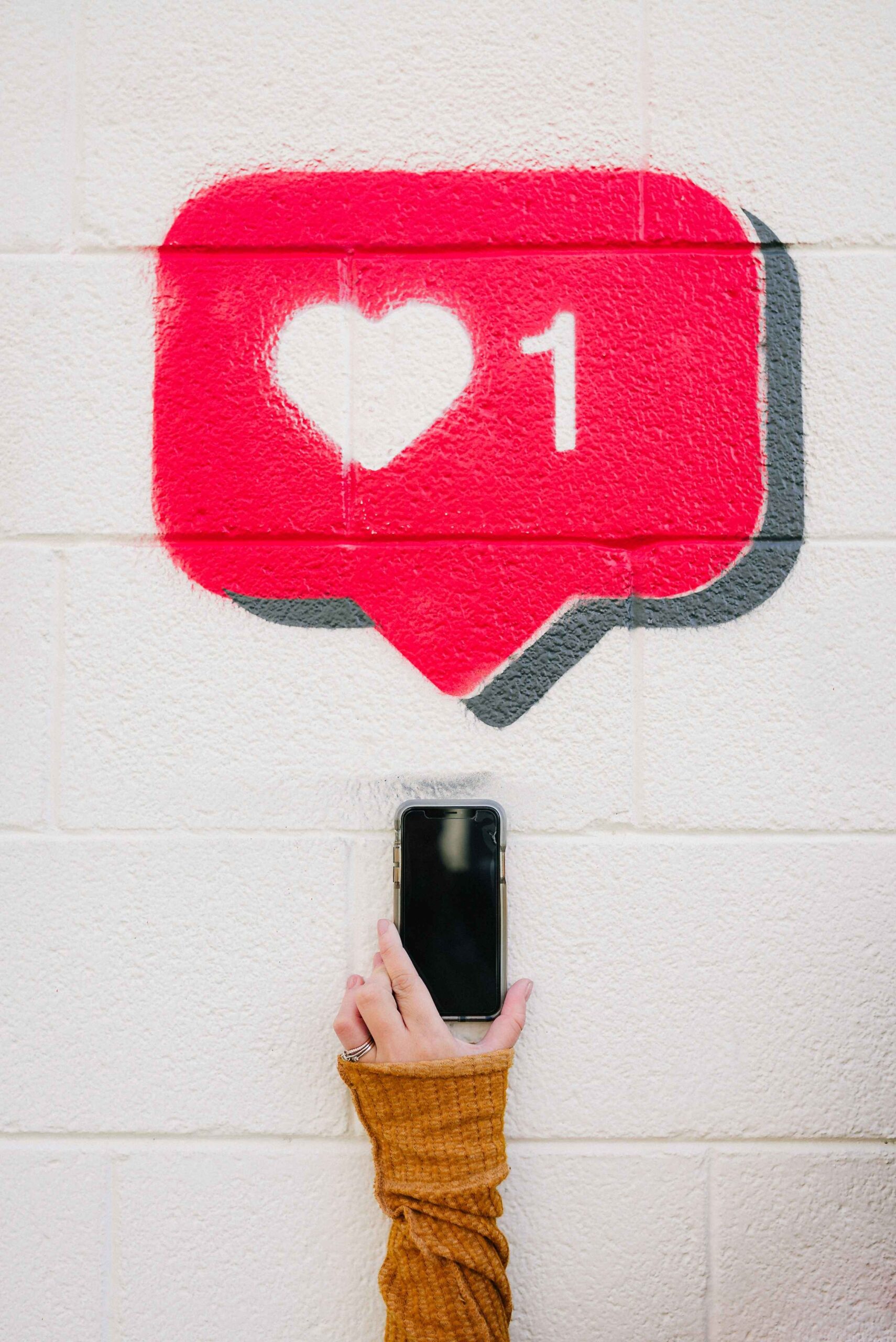 An illustration of a heart icon for likes next to a hand holding a smartphone