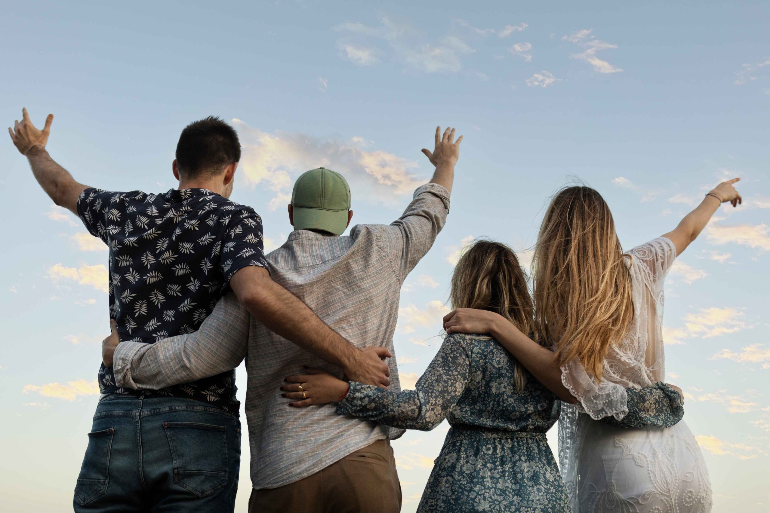 Friends embracing while looking out at the ocean on a sandy beach