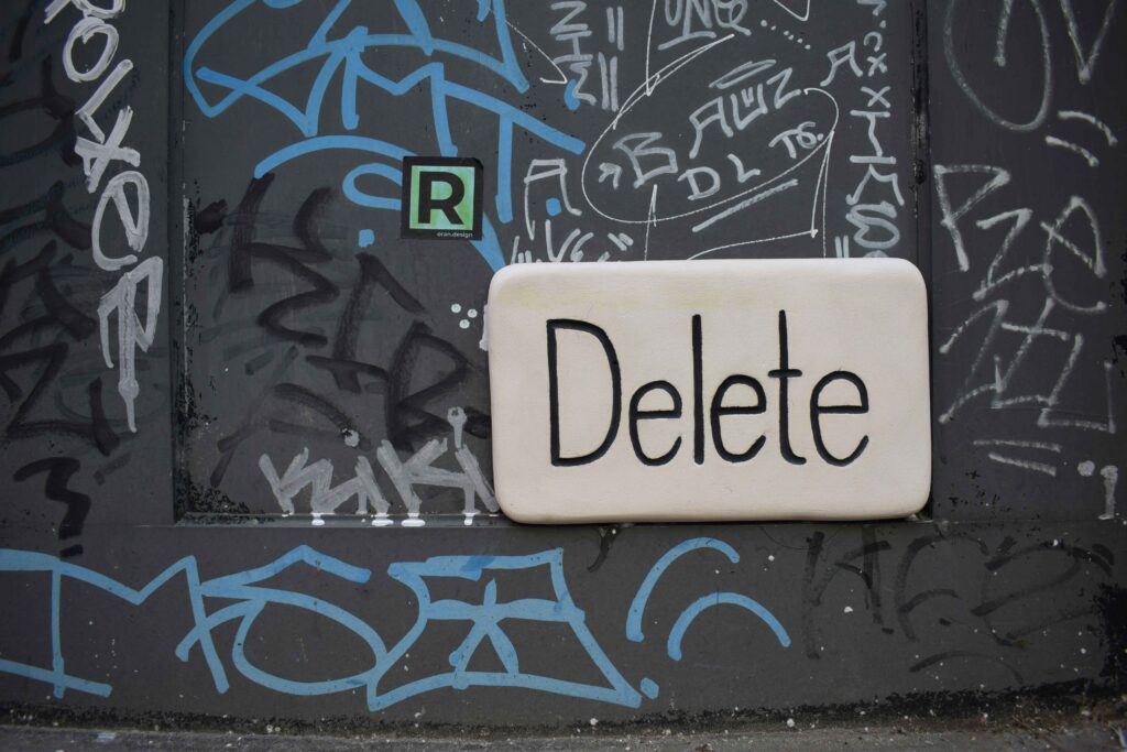 The word 'Delete' written on a graffiti-covered wall